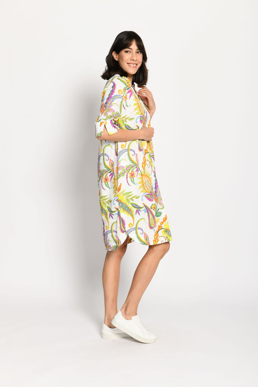 Model trägt knieumspielendes, luftiges Baumwollkleid mit farbenfrohem Muster auf weißem Untergrund – Seitenansicht links