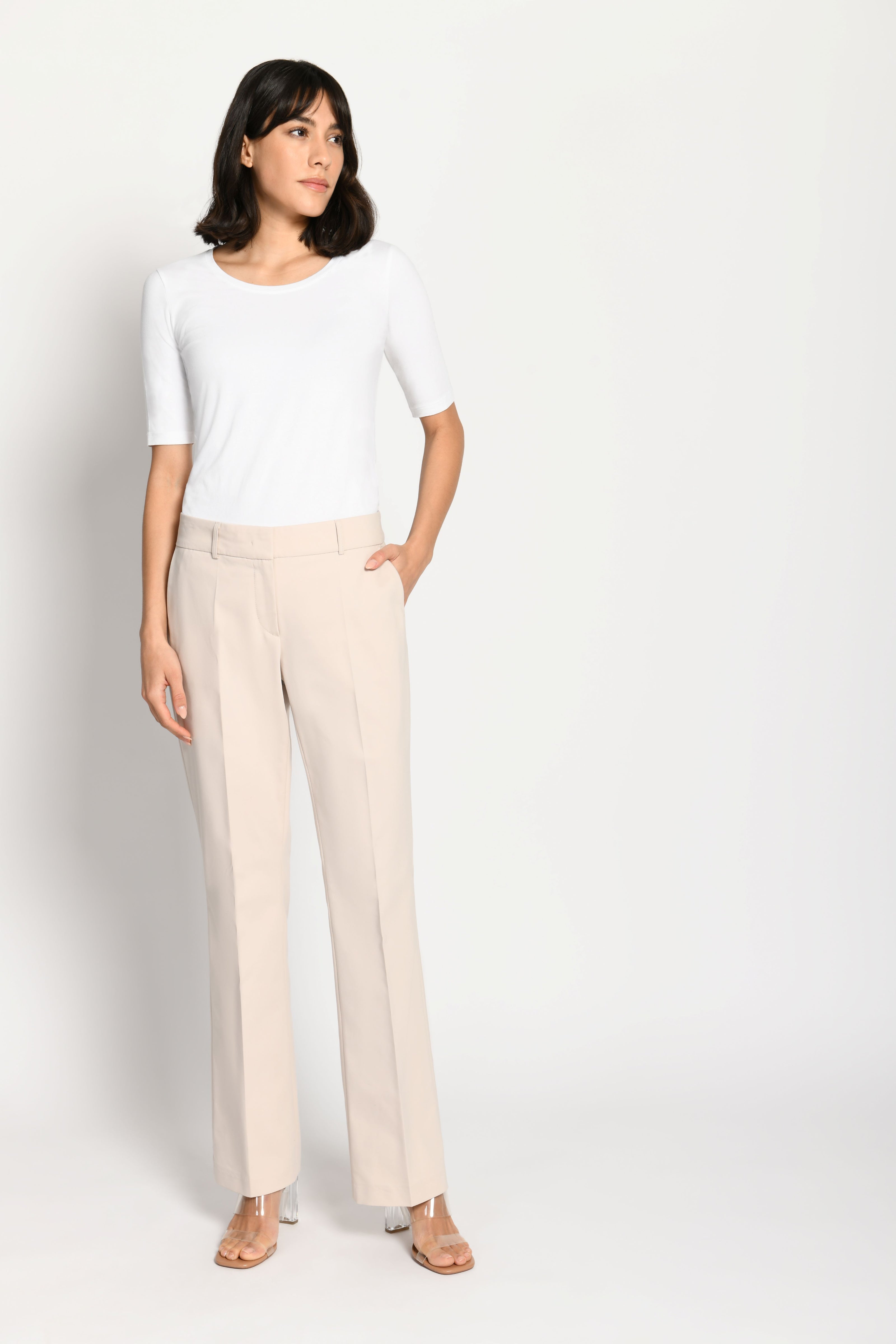 Model trägt beige Stoffhose für Damen mit Buntfalte – stehende Pose, Blick nach rechts