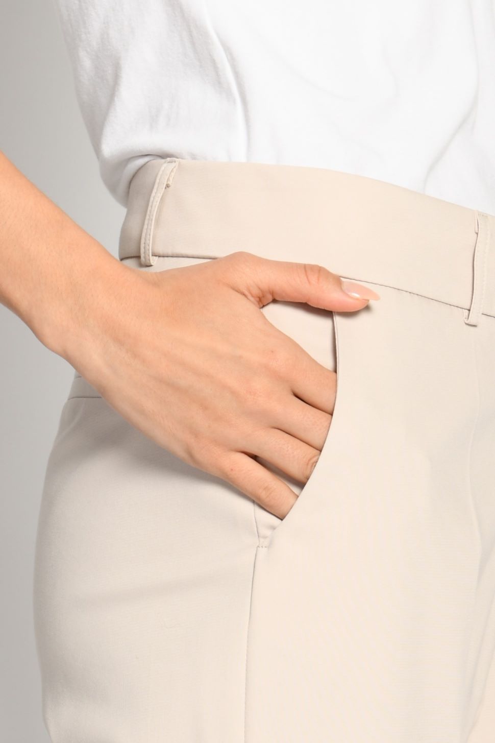 Nahaufnahme der beigen Stoffhose mit sichtbaren Gürtelschlaufen und seitlicher Leistentasche – Seitenansicht von links