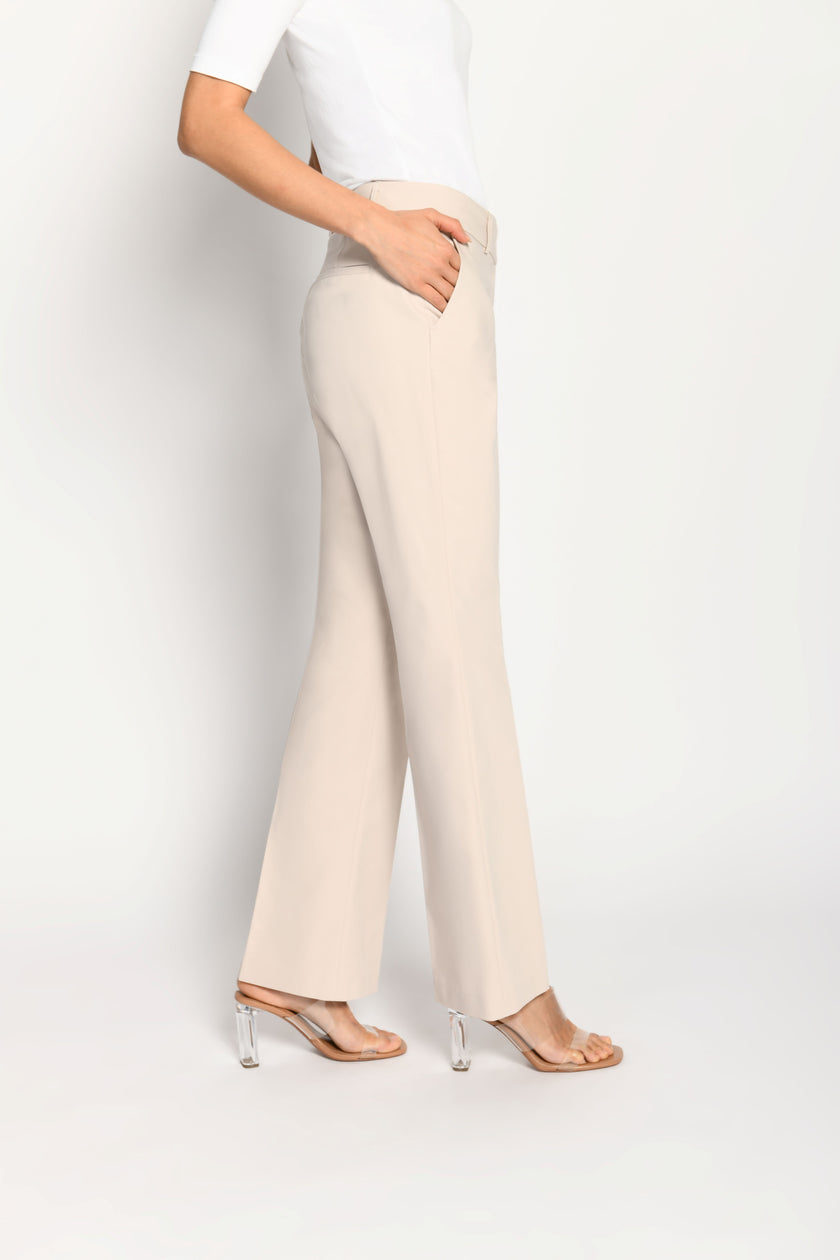 Model trägt beige Stoffhose für Damen mit Buntfalte – gehende Pose, Seitenansicht links