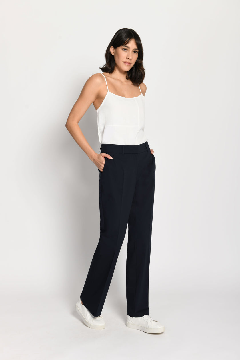 Model trägt dunkelblaue Stoffhose für Damen mit Buntfalte – gehende Pose, Seitenansicht links