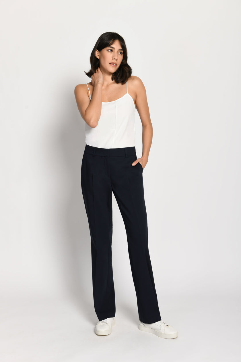 Model trägt dunkelblaue Stoffhose für Damen mit Buntfalte – stehende Pose, Blick nach rechts