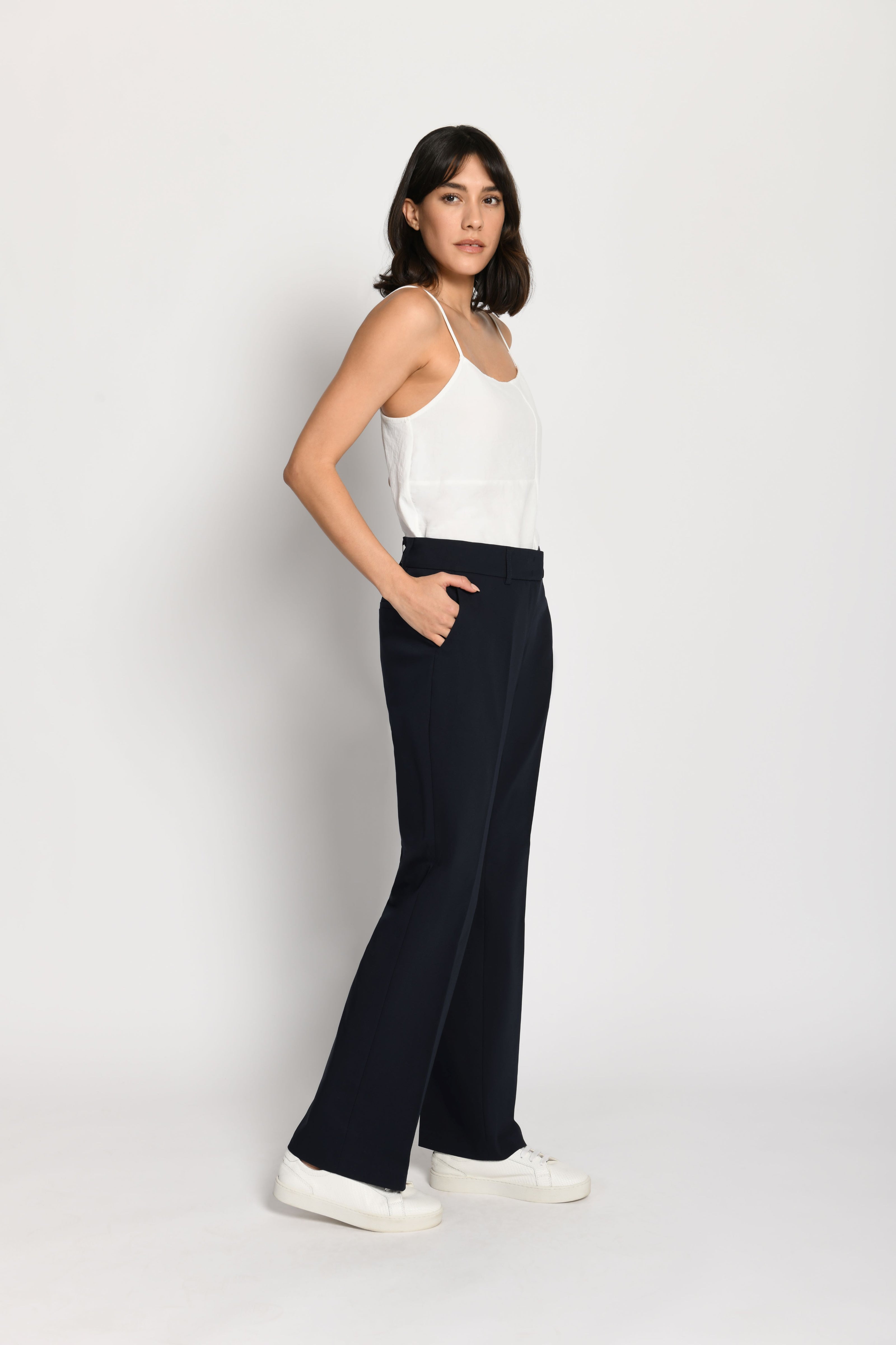 Model trägt dunkelblaue Stoffhose für Damen mit Buntfalte – stehende Pose, Seitenansicht links