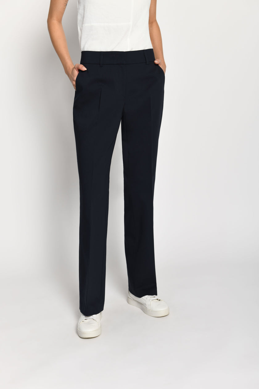 Model trägt dunkelblaue Stoffhose für Damen mit Buntfalte – stehende Pose, Vorderansicht