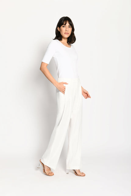 Model trägt weiße Marlene-Hose für Damen mit schmalen Leistentaschen – stehende Pose, Blick nach vorne