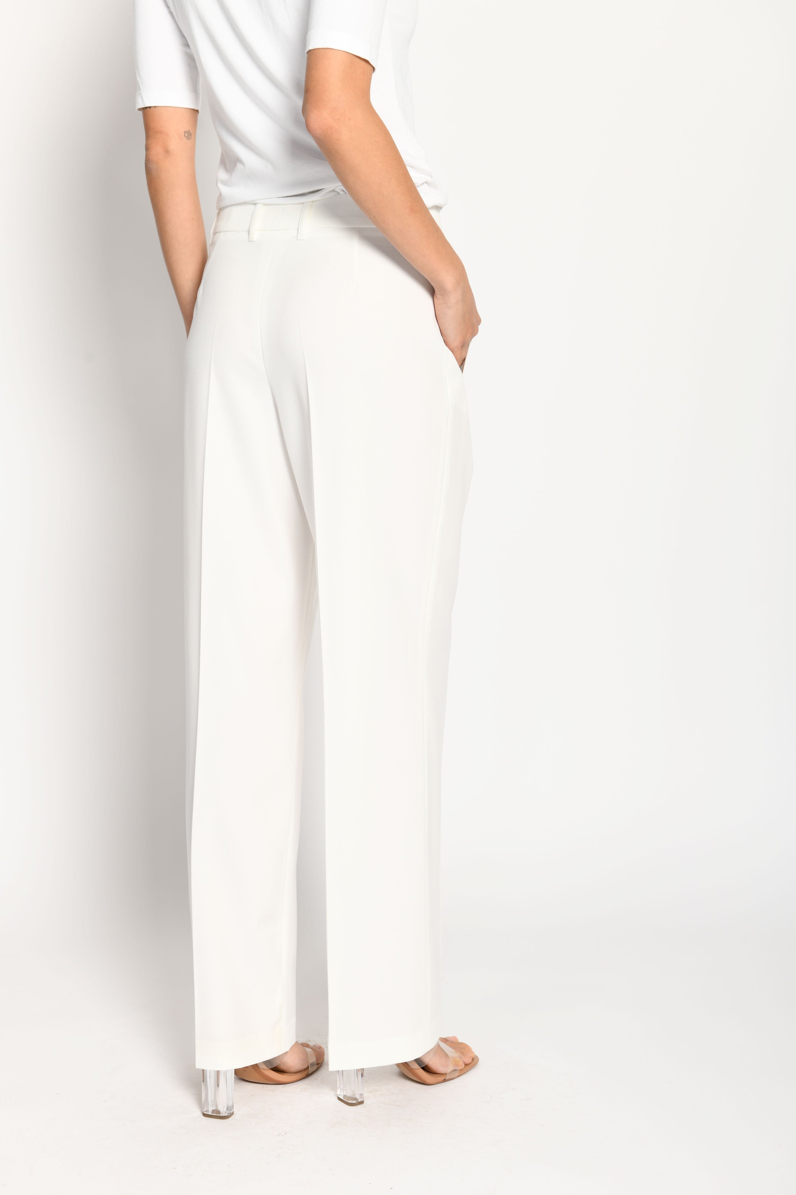 Model trägt weiße Marlene-Hose für Damen mit Buntfalte – stehende Pose, Rückansicht