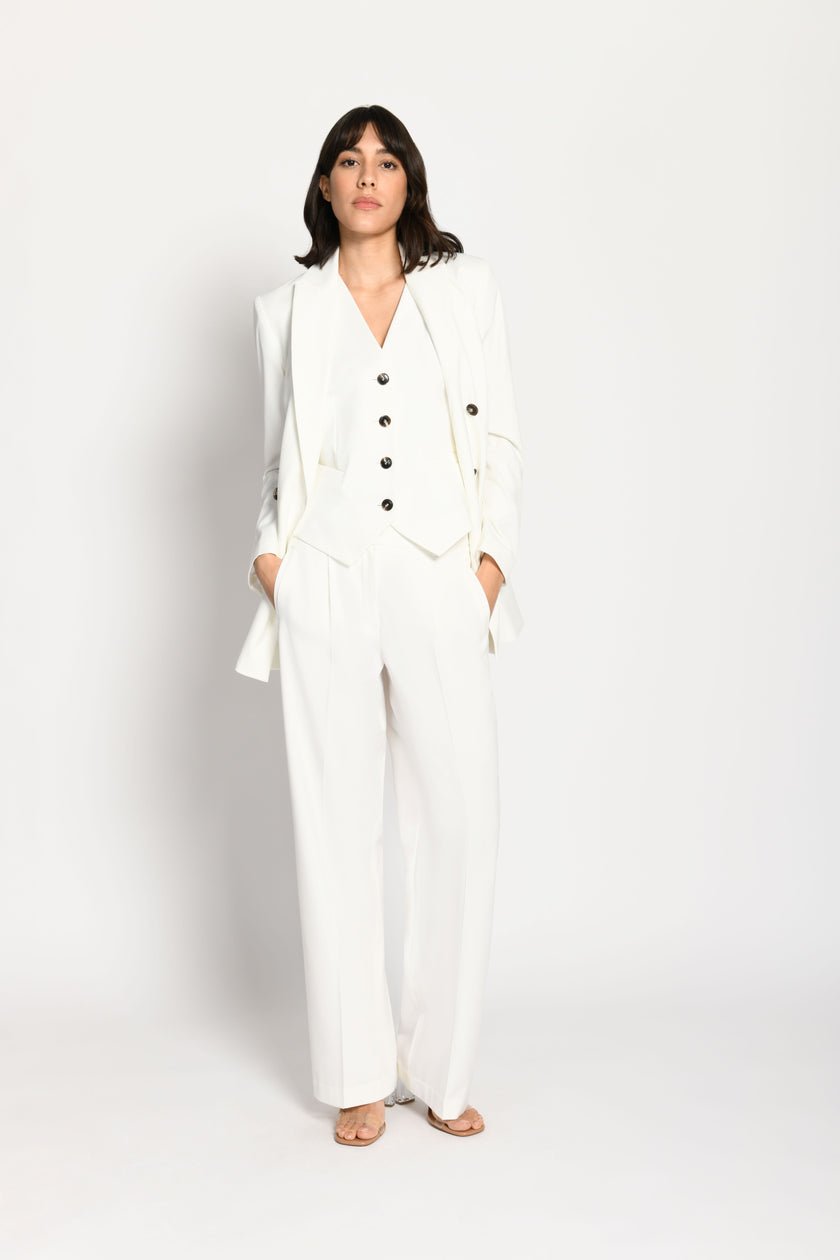 Model trägt taillierten weißen Damenblazer in Kombination mit passender weißer Stoffhose und Weste – Vorderseite, stehend