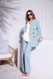 Model trägt hellblauen Hosenanzug aus Blazer und passender Stoffhose mit weißer Bluse kombiniert – Vorderansicht