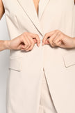 Detailaufnahme von Knopfverschluss und Pattentaschen des beigen ärmellosen Blazers – Vorderansicht