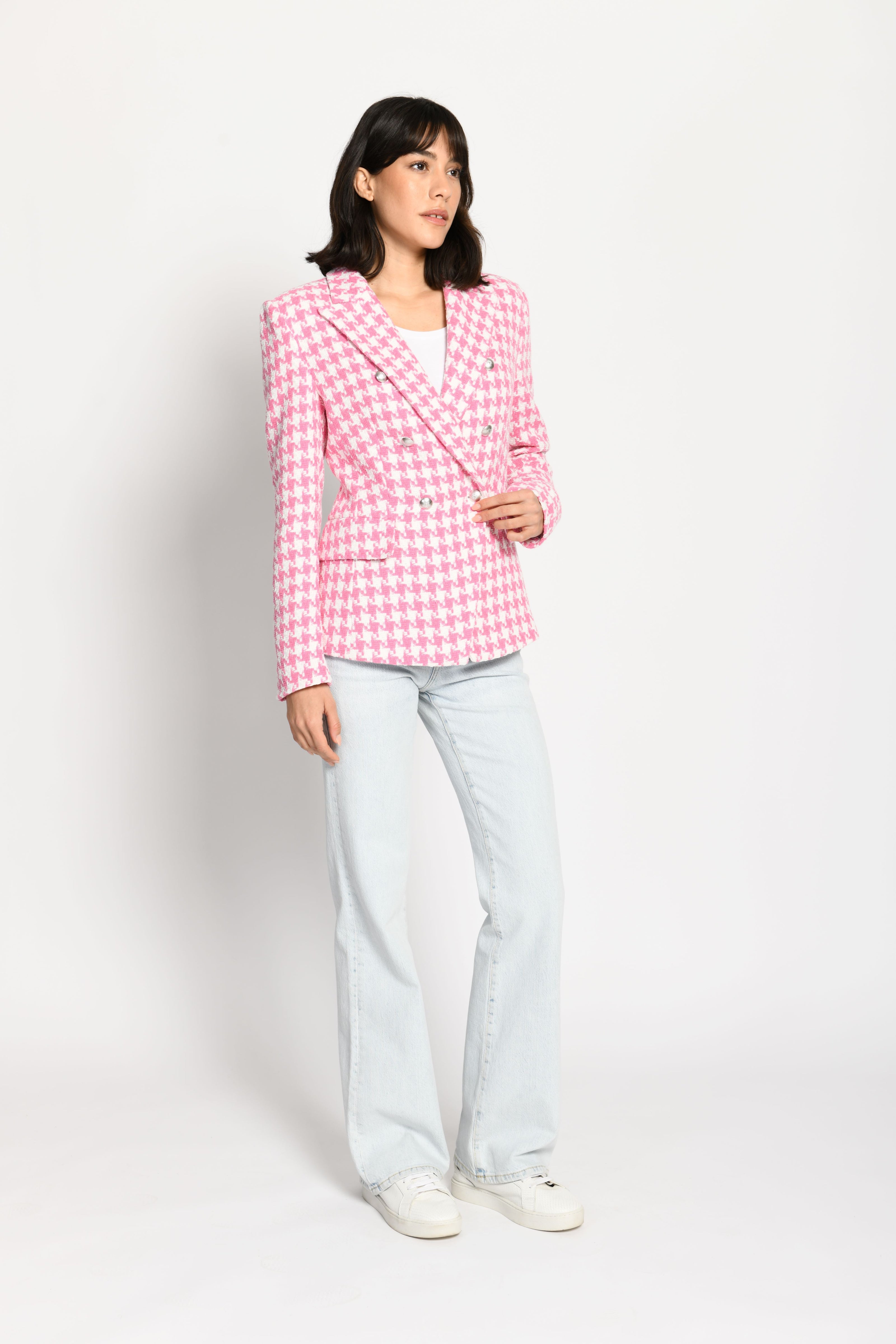 Model trägt leicht taillierten Damenblazer mit kräftigem Pepita-Muster in Rosa und Weiß – stehende Pose, Blick nach vorne