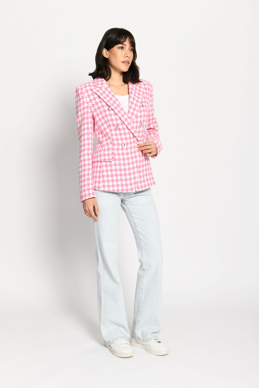 Model trägt leicht taillierten Damenblazer mit kräftigem Pepita-Muster in Rosa und Weiß – stehende Pose, Blick nach vorne
