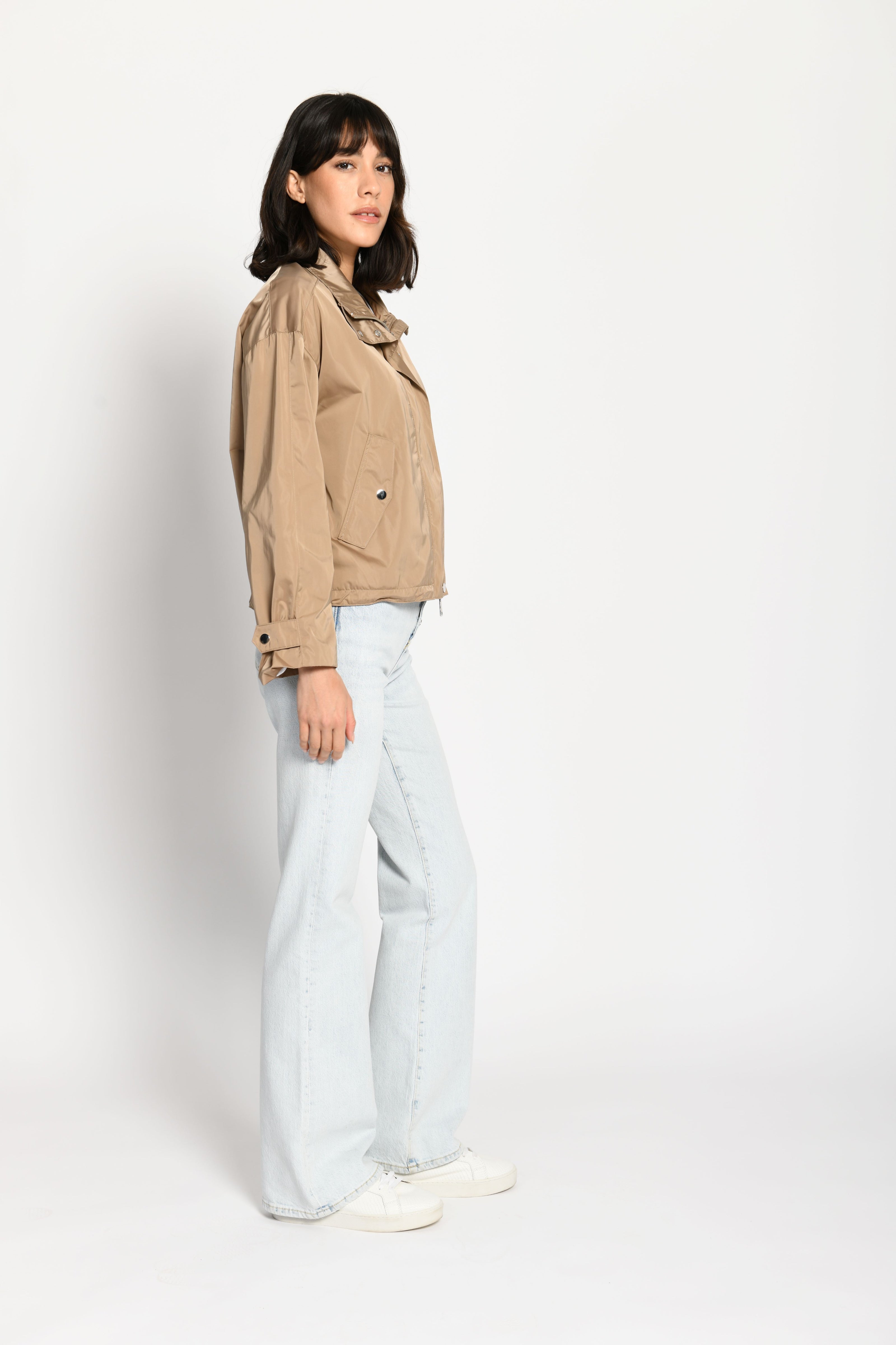 Lässig geschnittene braune Damenjacke mit sichtbarem Ärmelrieger – stehende seitliche Pose, Blick nach vorne