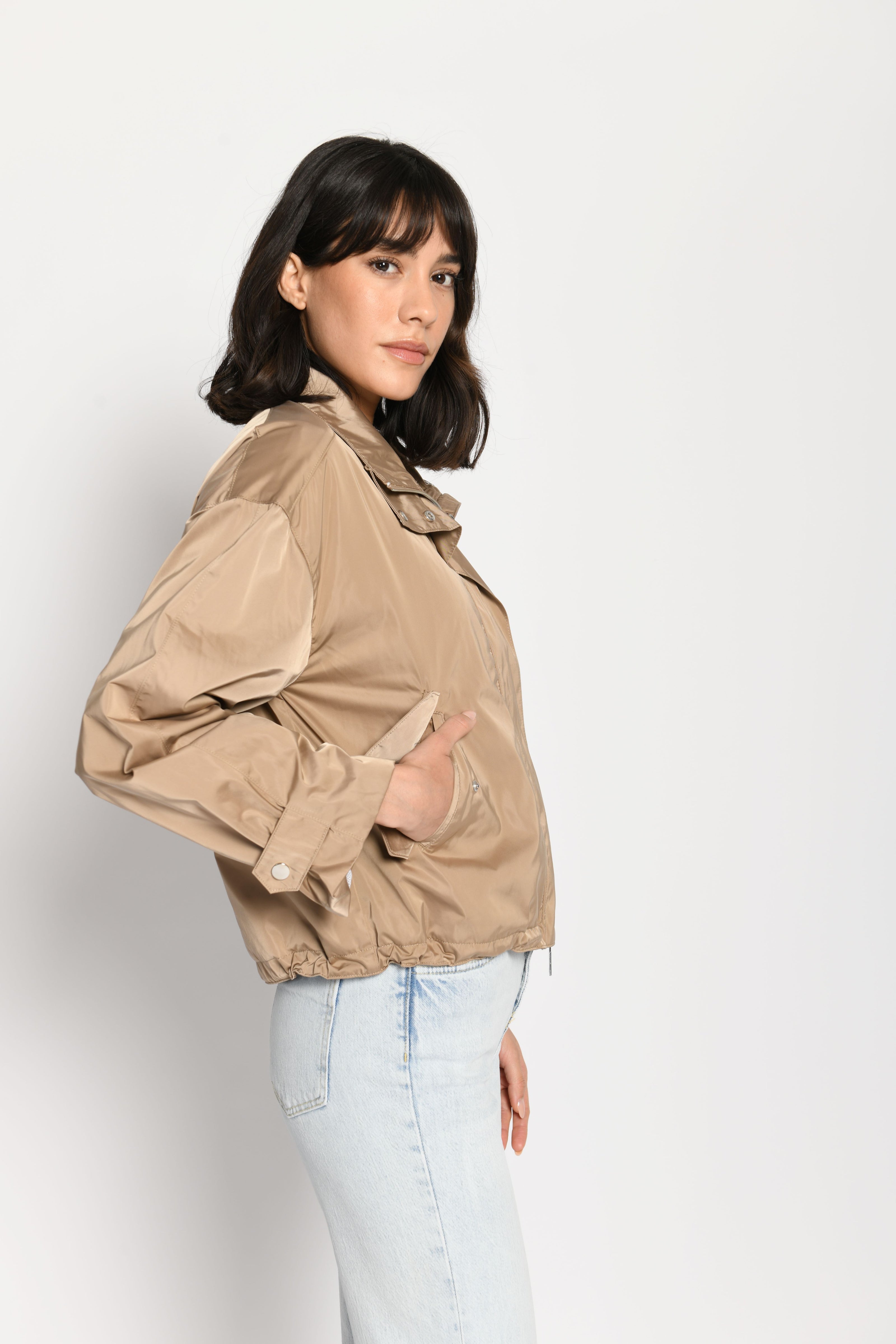 Lässig geschnittene braune Damenjacke mit Hand in der Tasche – stehende seitliche Pose