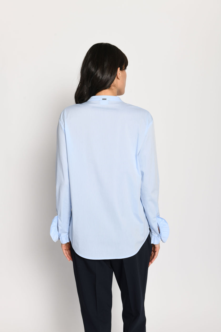 Model trägt hellblaue, locker sitzende Damenbluse mit Rüschen an den Ärmeln – Rückansicht