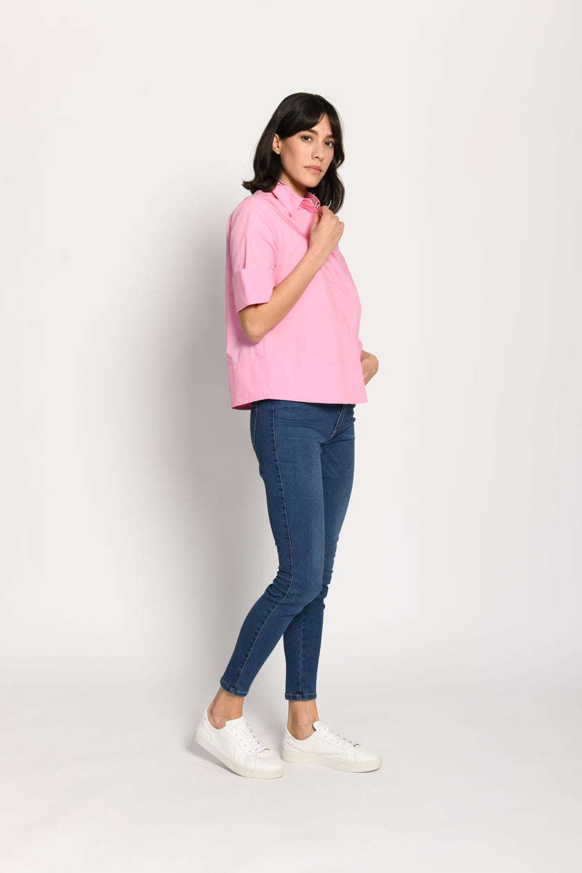 Model trägt kurze kastige Boxy-Bluse in der Farbe Pink mit kurzen Ärmeln, passend zu einer Jeans – Seitenansicht von links