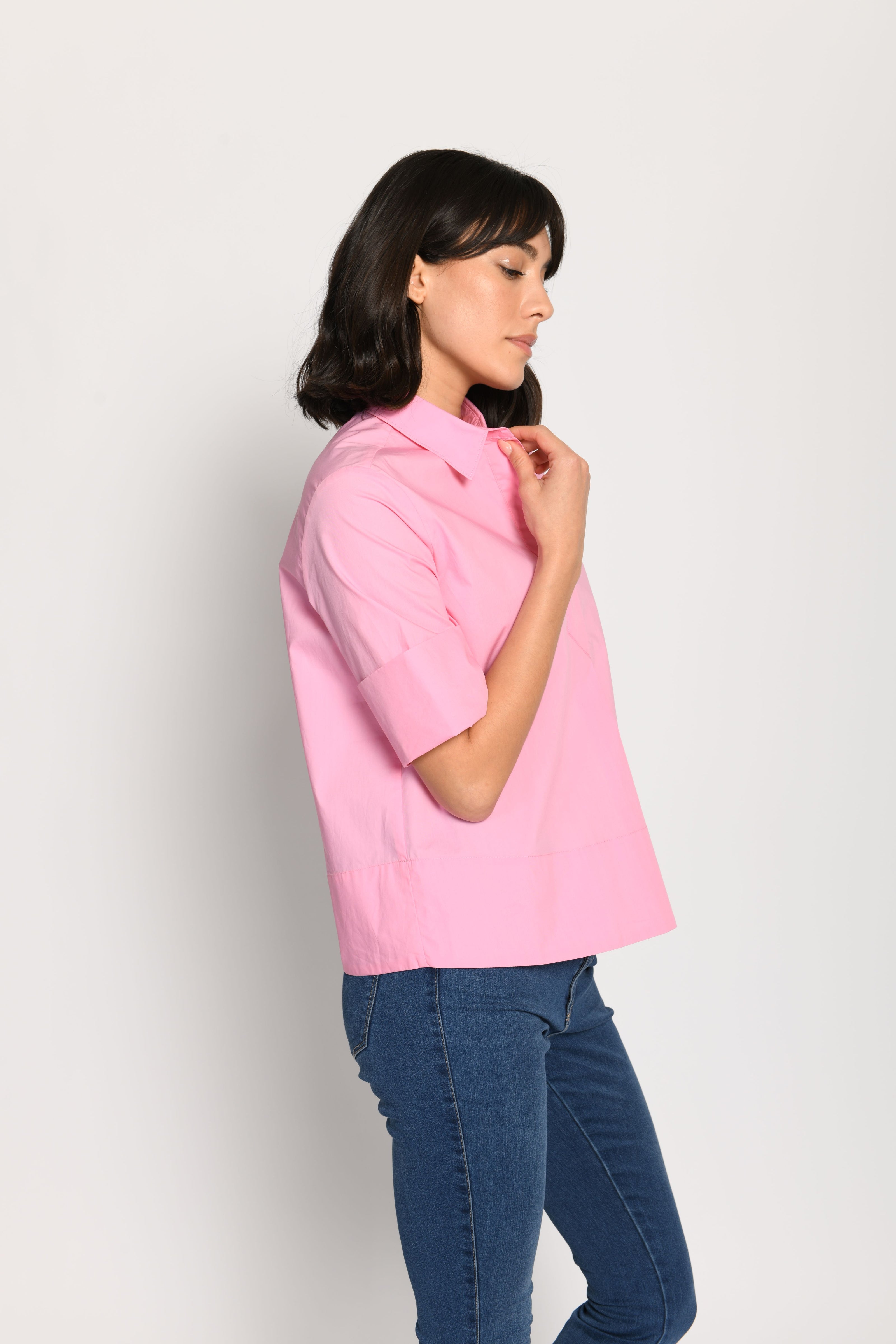 Model trägt kurze kastige Boxy-Bluse in der Farbe Pink mit kurzen Ärmeln, passend zu einer Jeans – Seitenansicht von links