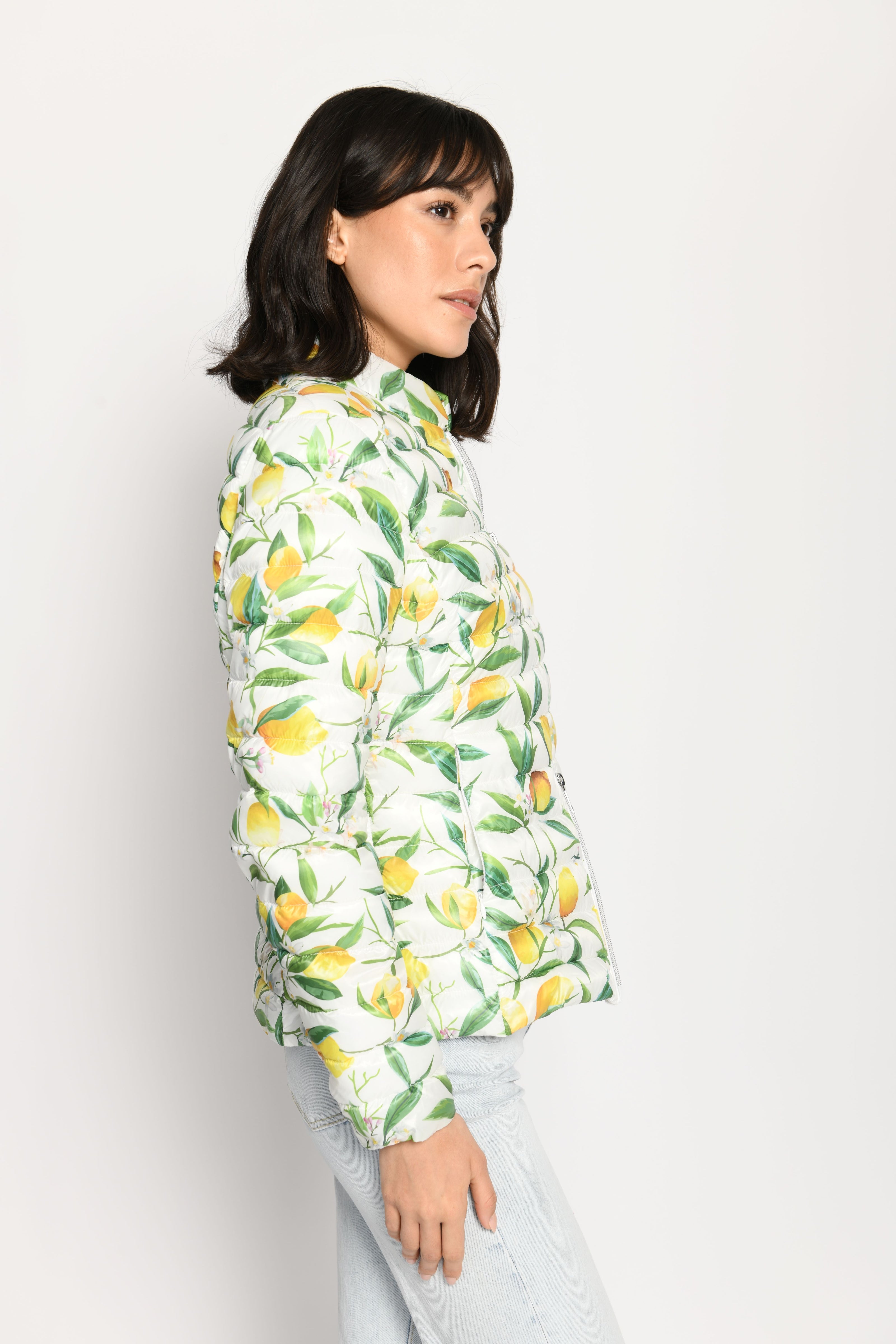 Model trägt leichte Steppjacke für Damen mit kräftigem Zitronen-Print auf weißer Jacke – Seitenansicht von links