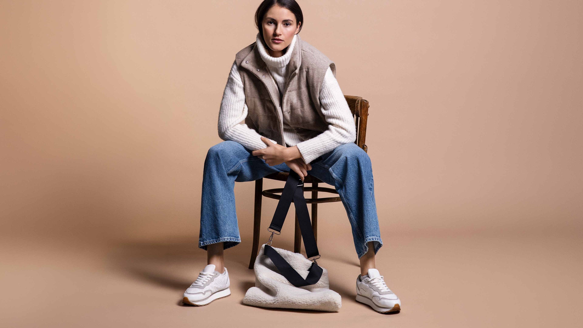 Model trägt sportliches Outfit mit Weste und dazu eine kuschelige Tasche