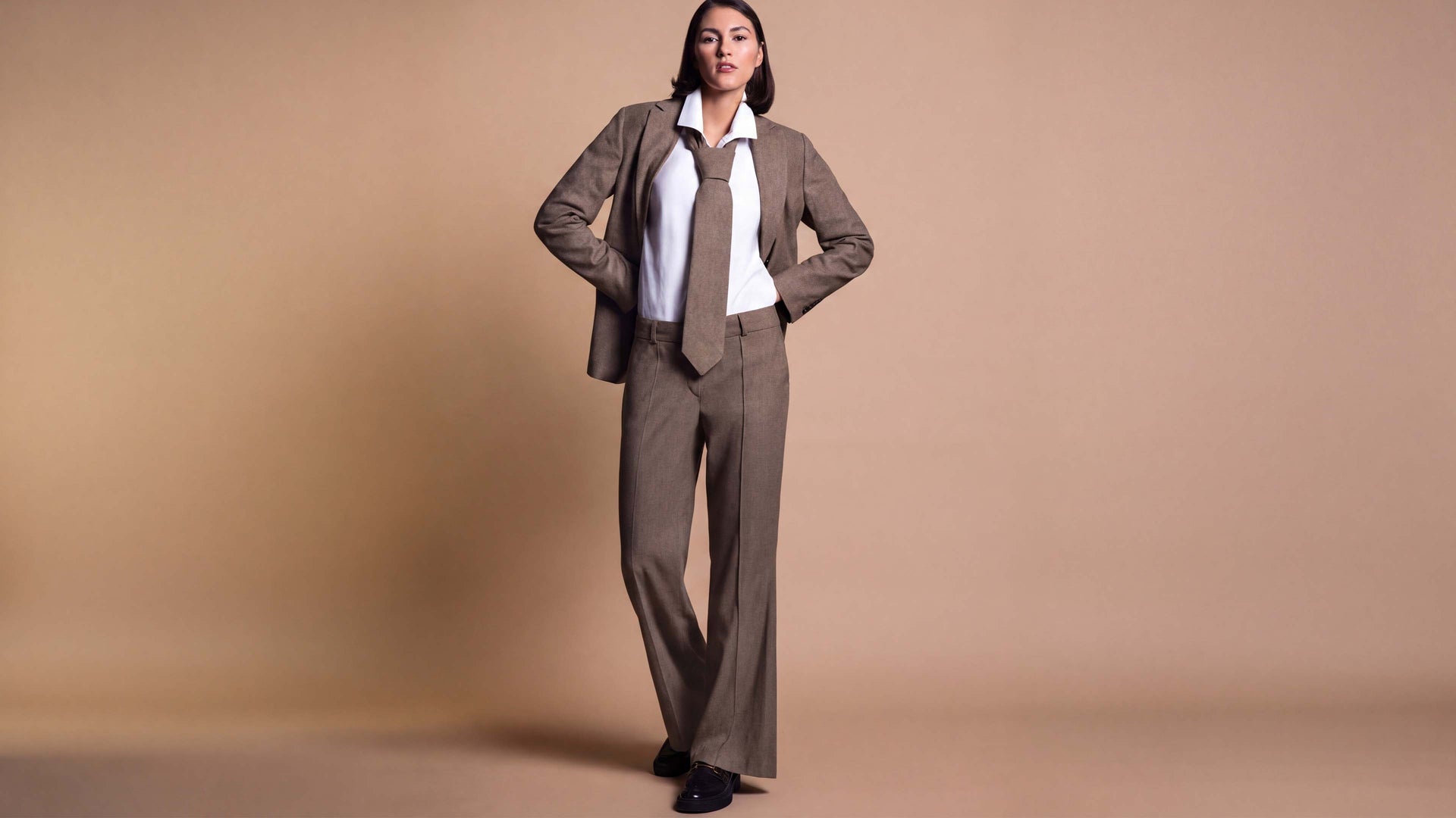 Das Model trägt eine Anzugkombi aus Hose und Blazer in der Farbe Stein.