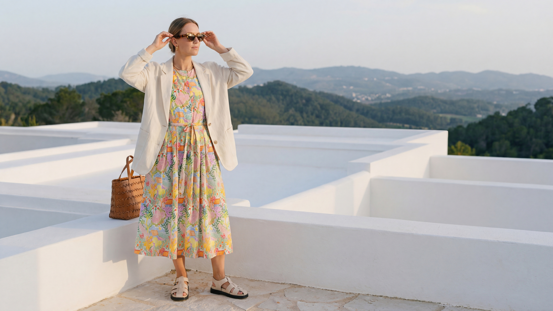 Model trägt buntes Sommerkleid mit Blazer und Sonnenbrille.