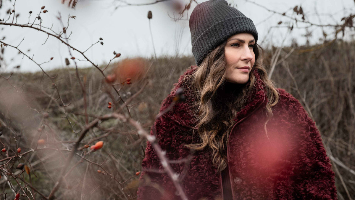 Model trägt kuschelige Jacke in dunklem rot.