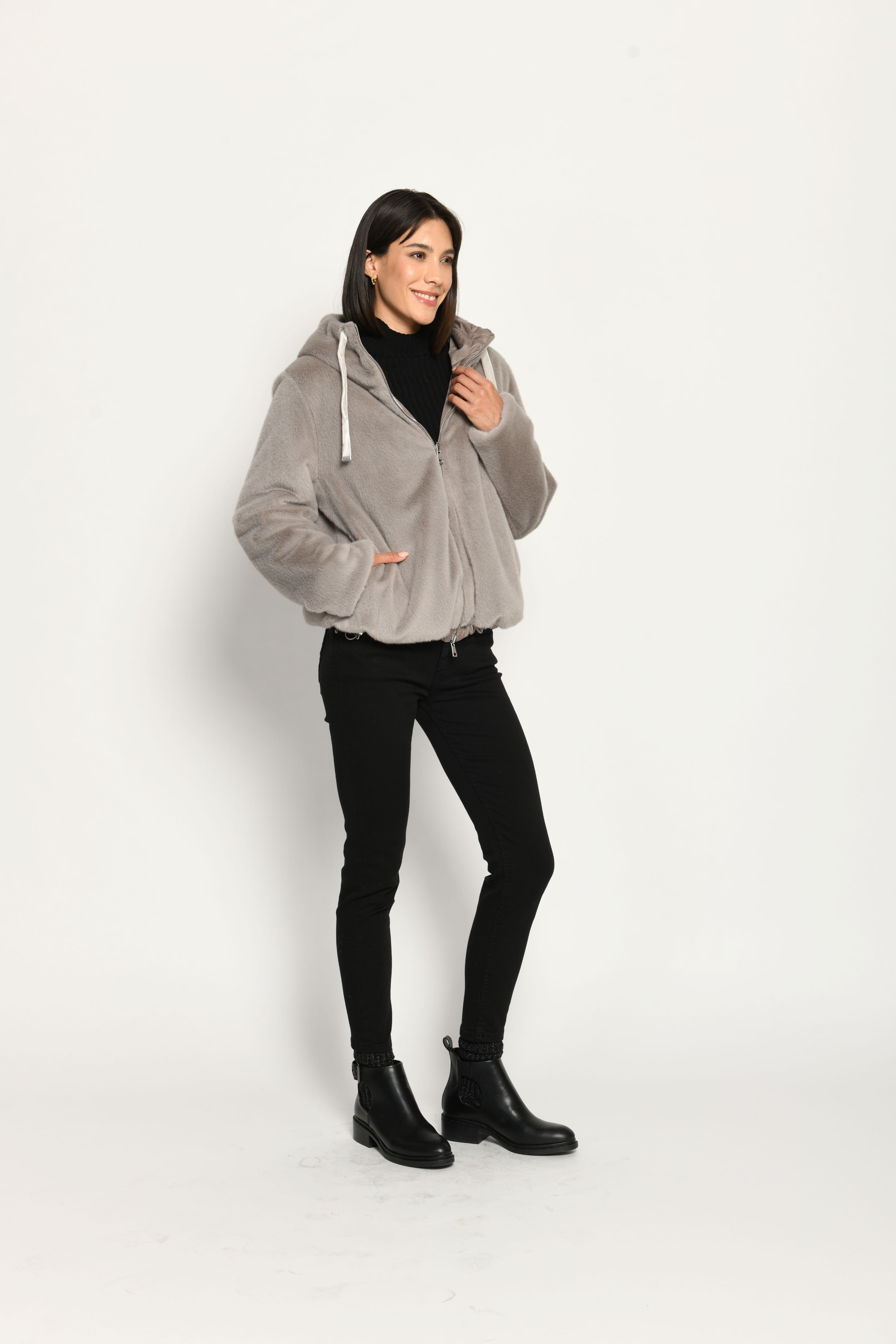 Wendejacke für Damen in der Farbe Taupe mit Webpelz als Außenseite, kombiniert zu schwarzer Jeans – seitlich stehend