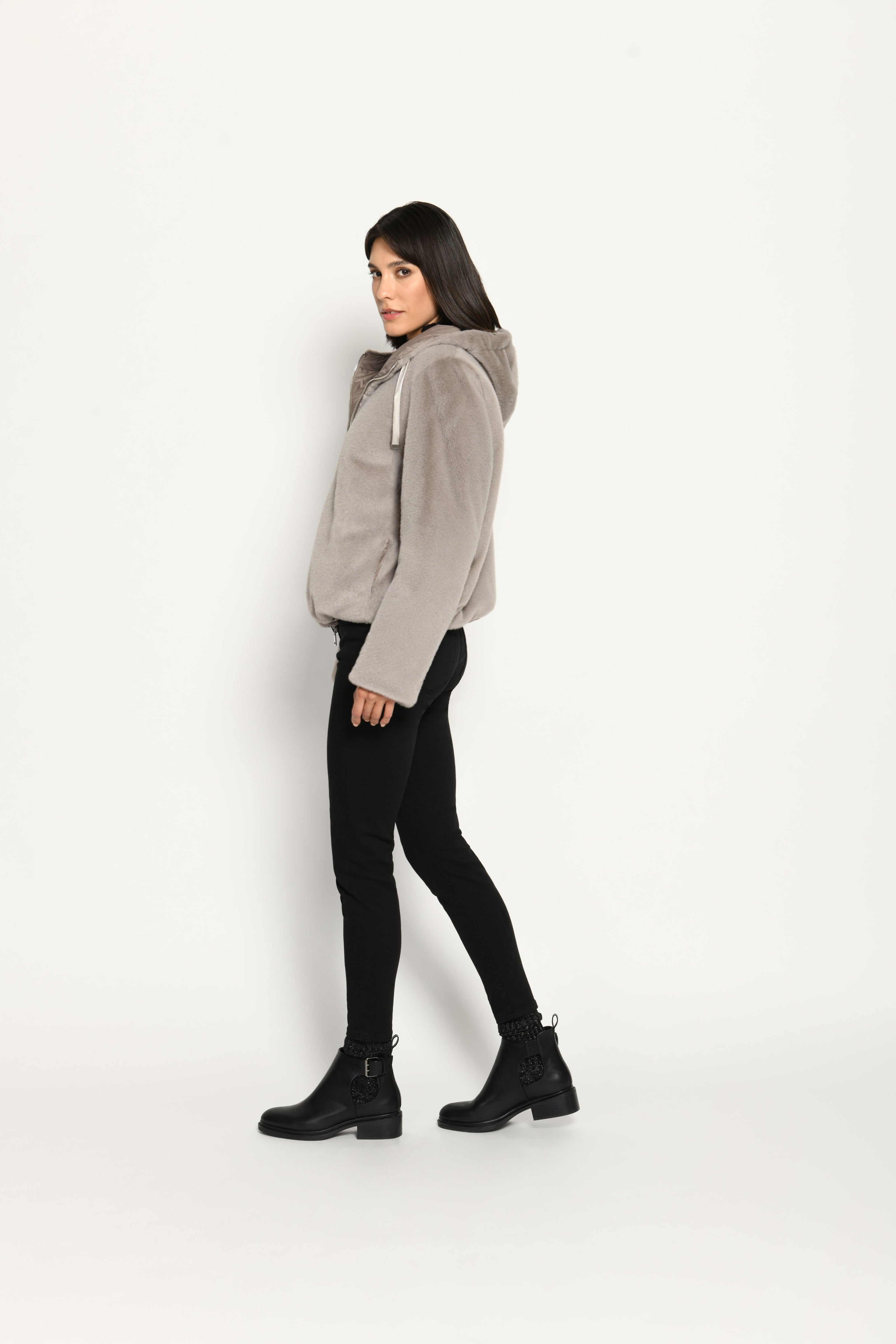 Wendejacke für Damen in der Farbe Taupe mit Webpelz als Außenseite, kombiniert zu schwarzer Jeans – Profil von links