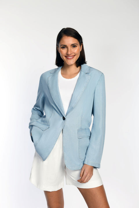 Model trägt geschlossenen Blazer in Jeansoptik mit aufgesetzten Taschen.