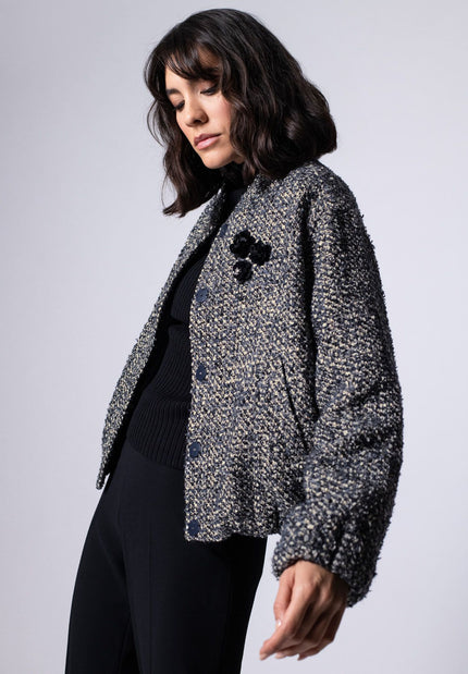 Offen getragener Bouclé-Blouson für Damen in den Farben Schwarz und Weiß, kombiniert zu dunkler Stoffhose – Seitenansicht