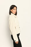 Cord-Blouson in der Farbe Creme mit großen Taschen und schwarzen Knöpfen, kombiniert zu schwarzer Hose – Profilansicht