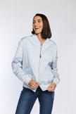 Model trägt blauen Blouson mit 2-Wege-Reißverschluss und aufgesetzter Reißverschlusstasche am Oberarm.