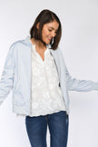 Model trägt offenen blauen Blouson, kombiniert mit weißer Bluse.