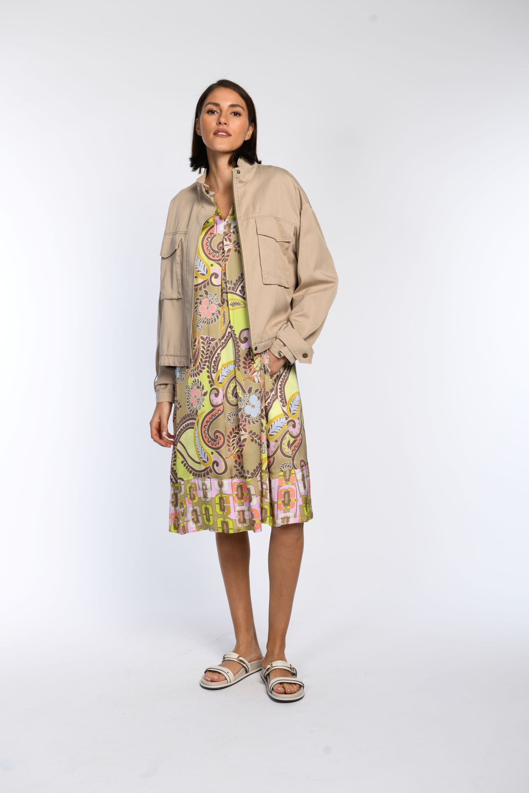 Model trägt ein braunfarbiges Blouson mit Stehkragen in Kombination mit einem bedruckten Tunikakleid.