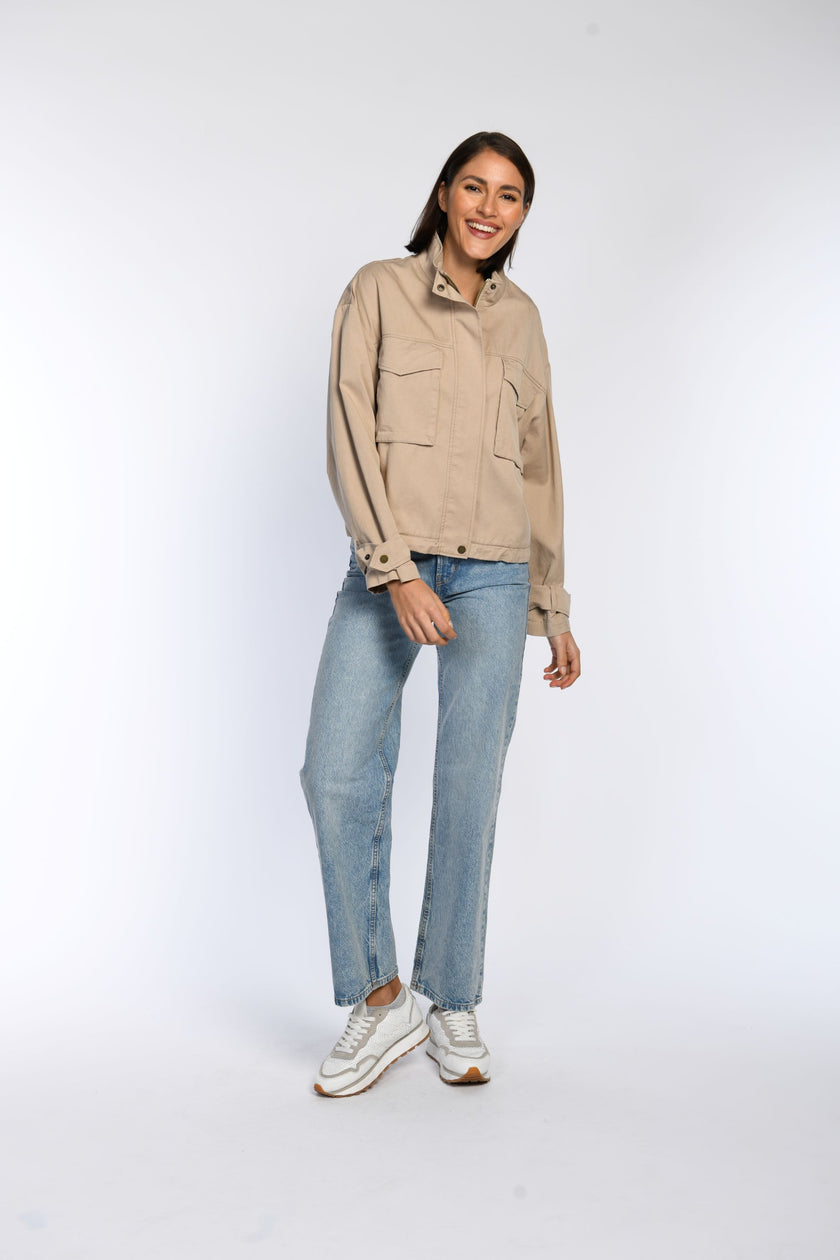 Model trägt geschlossenes braunes Blouson mit Stehkragen und großen aufgesetzten Taschen.