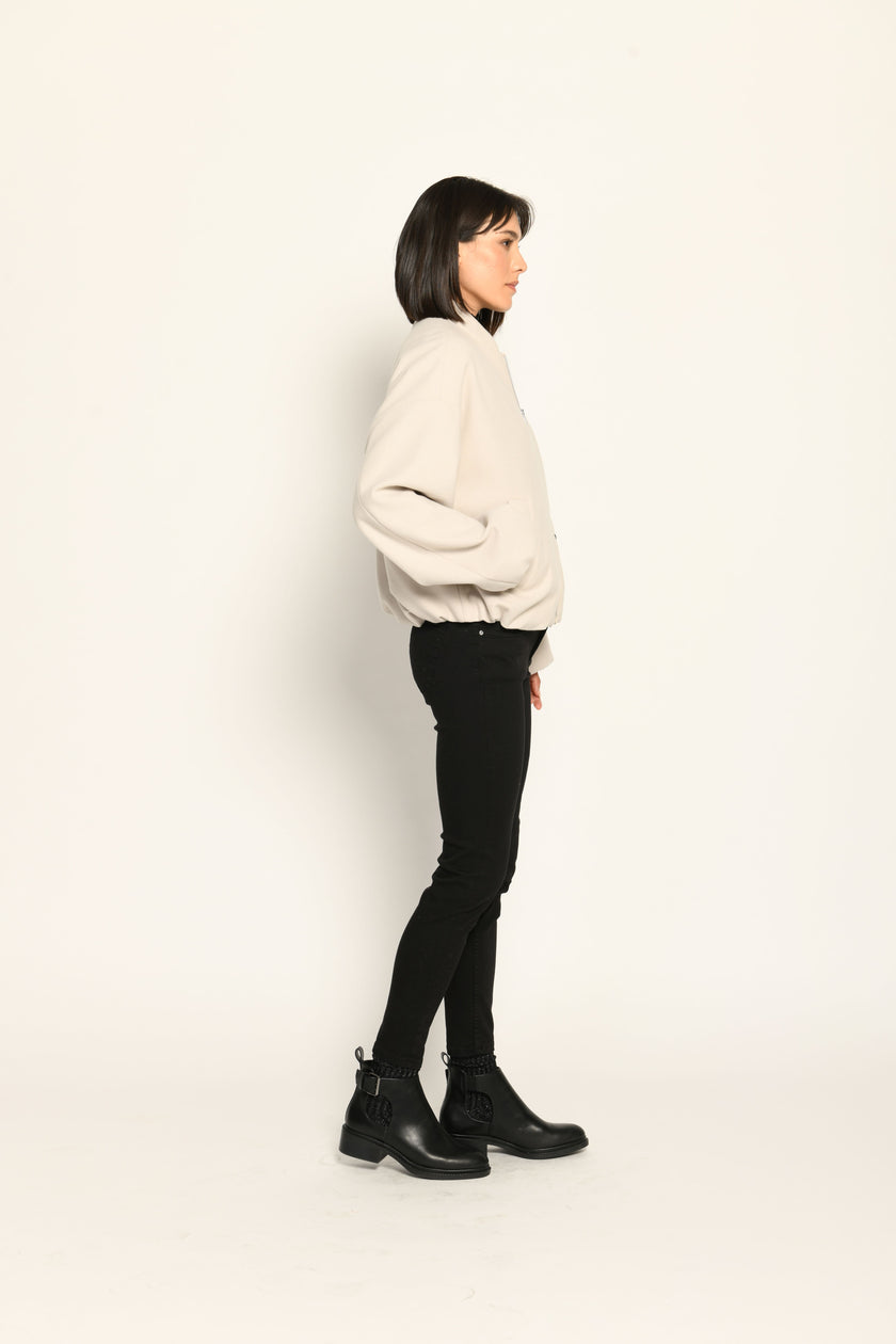 Model trägt oversized geschnittenen cremefarbenen Blouson für Damen zu schwarzer Jeans – Seitenansicht rechts