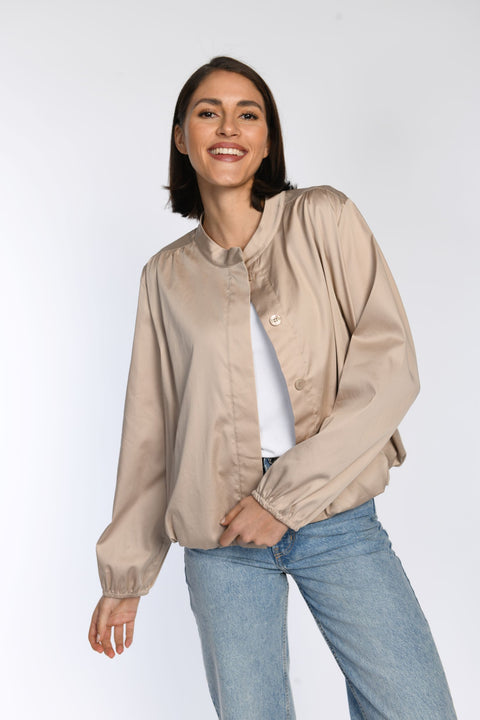 Model trägt taupefarbenes Blouson mit Stehkragen und Leistentaschen - Vorderansicht.