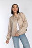 Model trägt taupefarbenes Blouson mit Stehkragen und Leistentaschen - Vorderansicht.