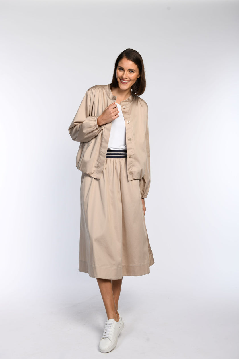 Model trägt ein taupefarbenes Blouson, kombiniert mit einem passenden taupefarbenen Rock.