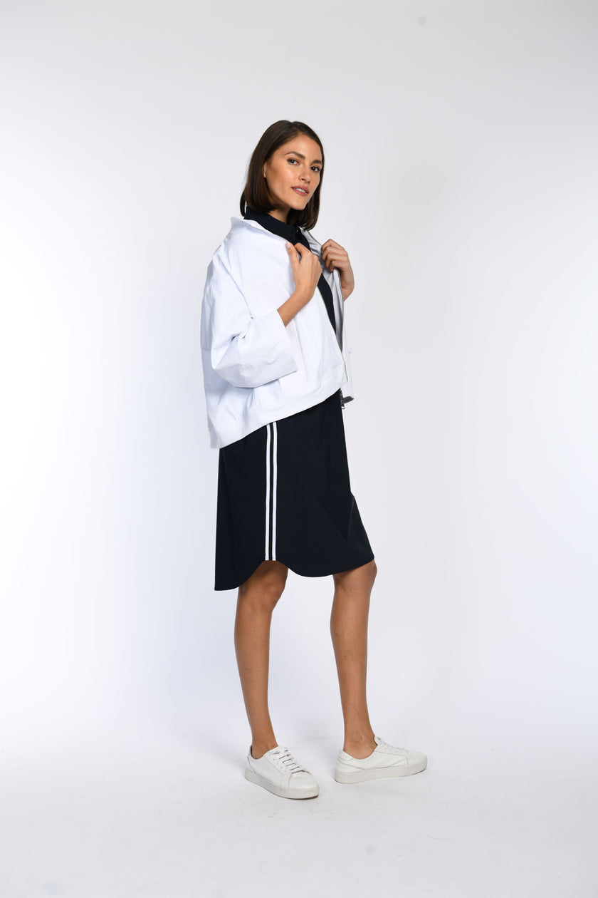 Model trägt eine oversized Jacke mit überschnittenen Schultern in Kombination mit einem sportlichen Kleid.