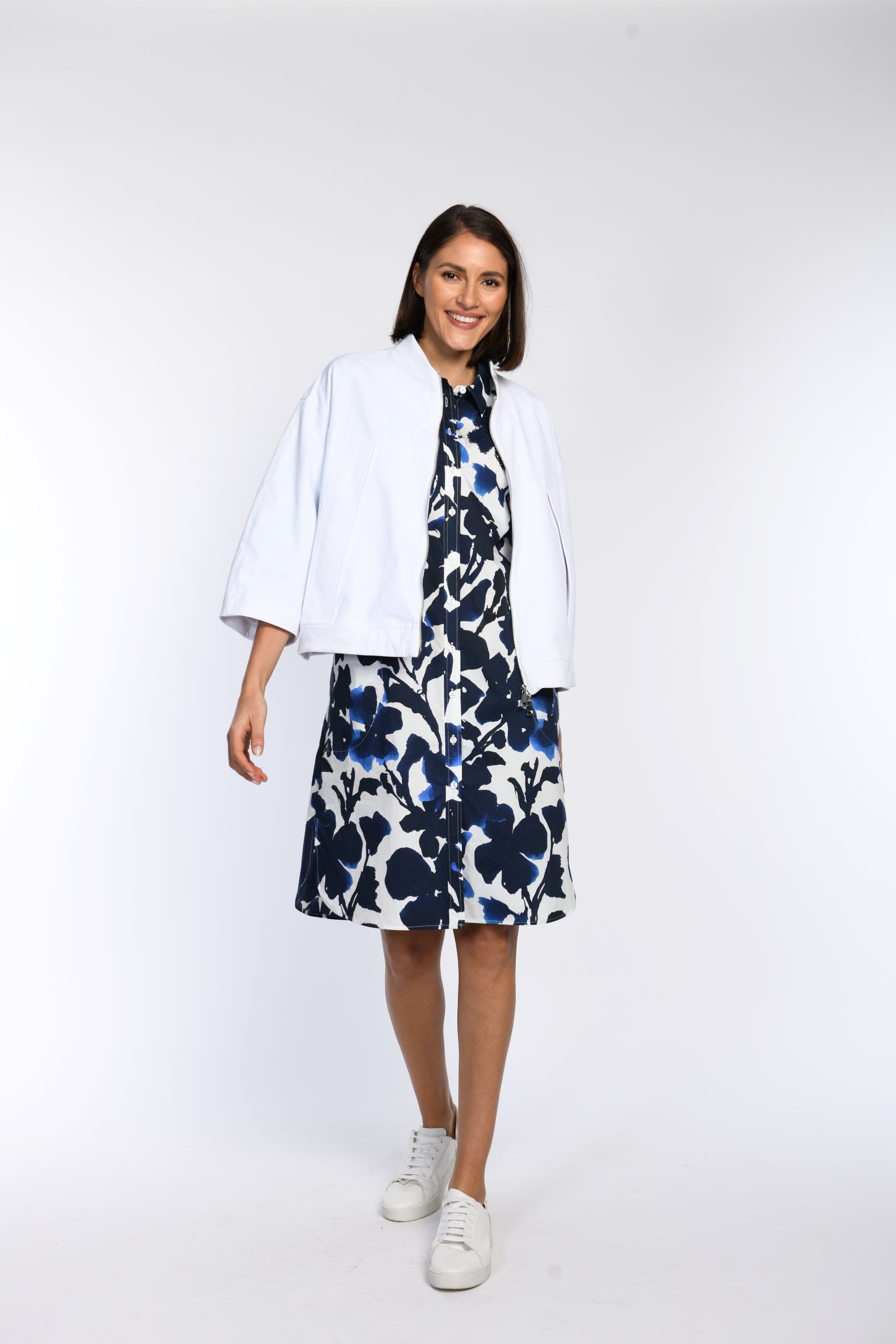 Model trägt  weiße oversized Jacke mit überschnittenen Schultern und Fledermausärmeln in Kombination mit einem Tunikakleid.