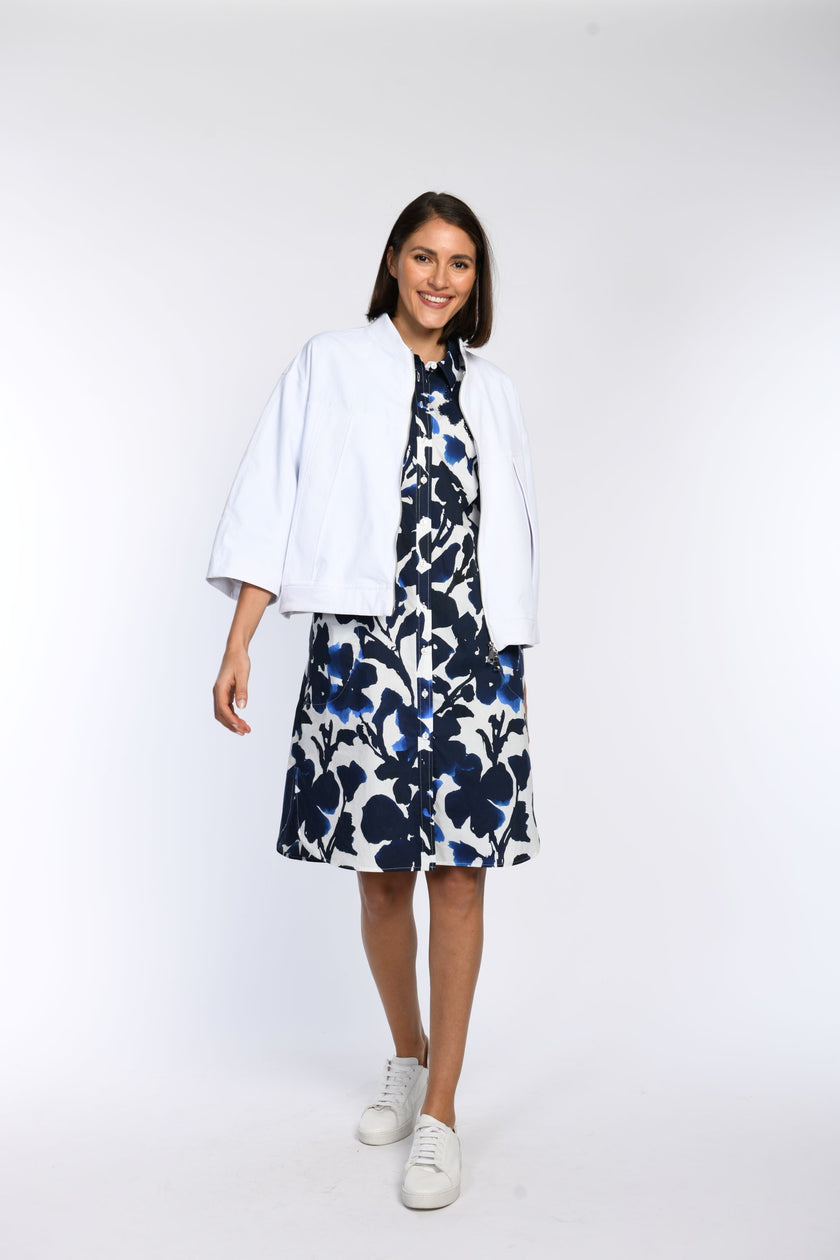 Model trägt  weiße oversized Jacke mit überschnittenen Schultern und Fledermausärmeln in Kombination mit einem Tunikakleid.