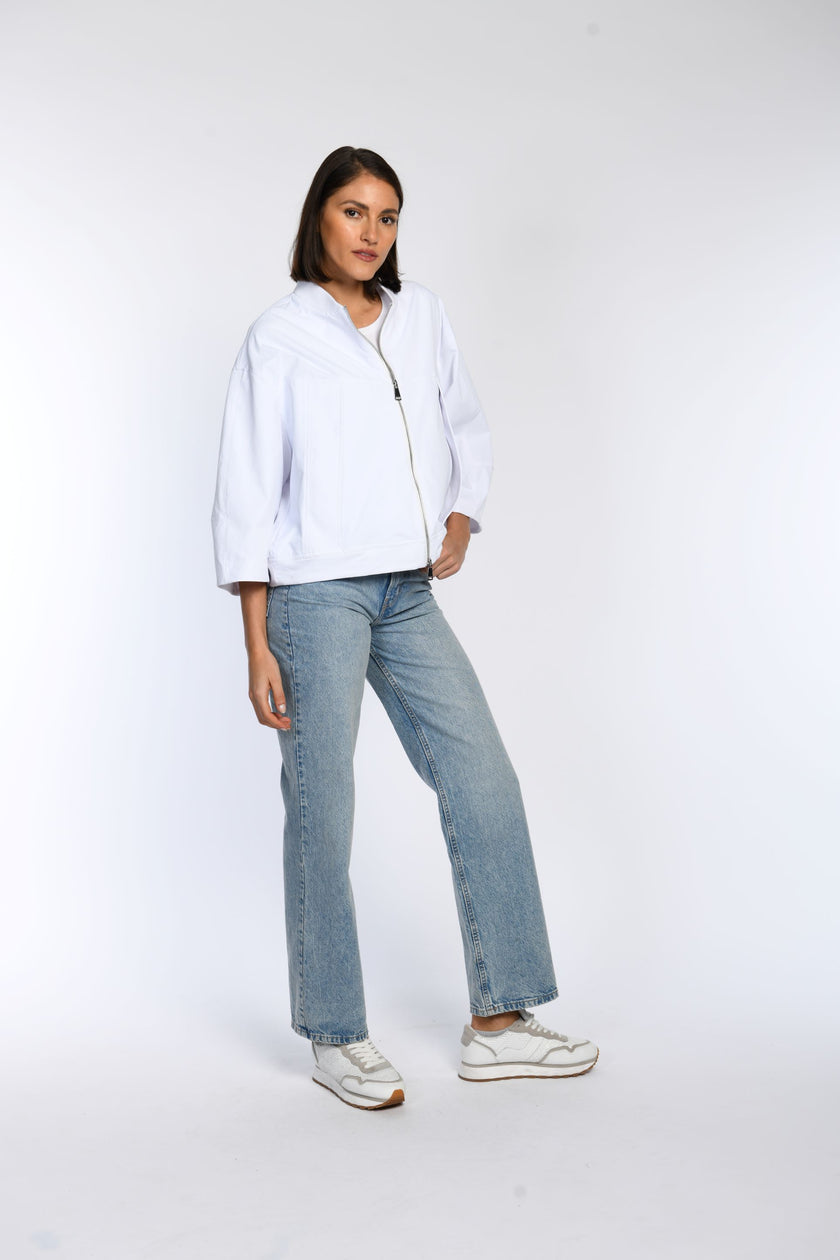 Model trägt weiße oversized Jacke mit 7/8-Ärmeln und überschnittenen Schultern – Seitenansicht. 