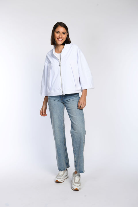Model trägt eine geschlossene weiße oversized Jacke mit 7/8-Ärmeln und Strick-Stehkragen. 