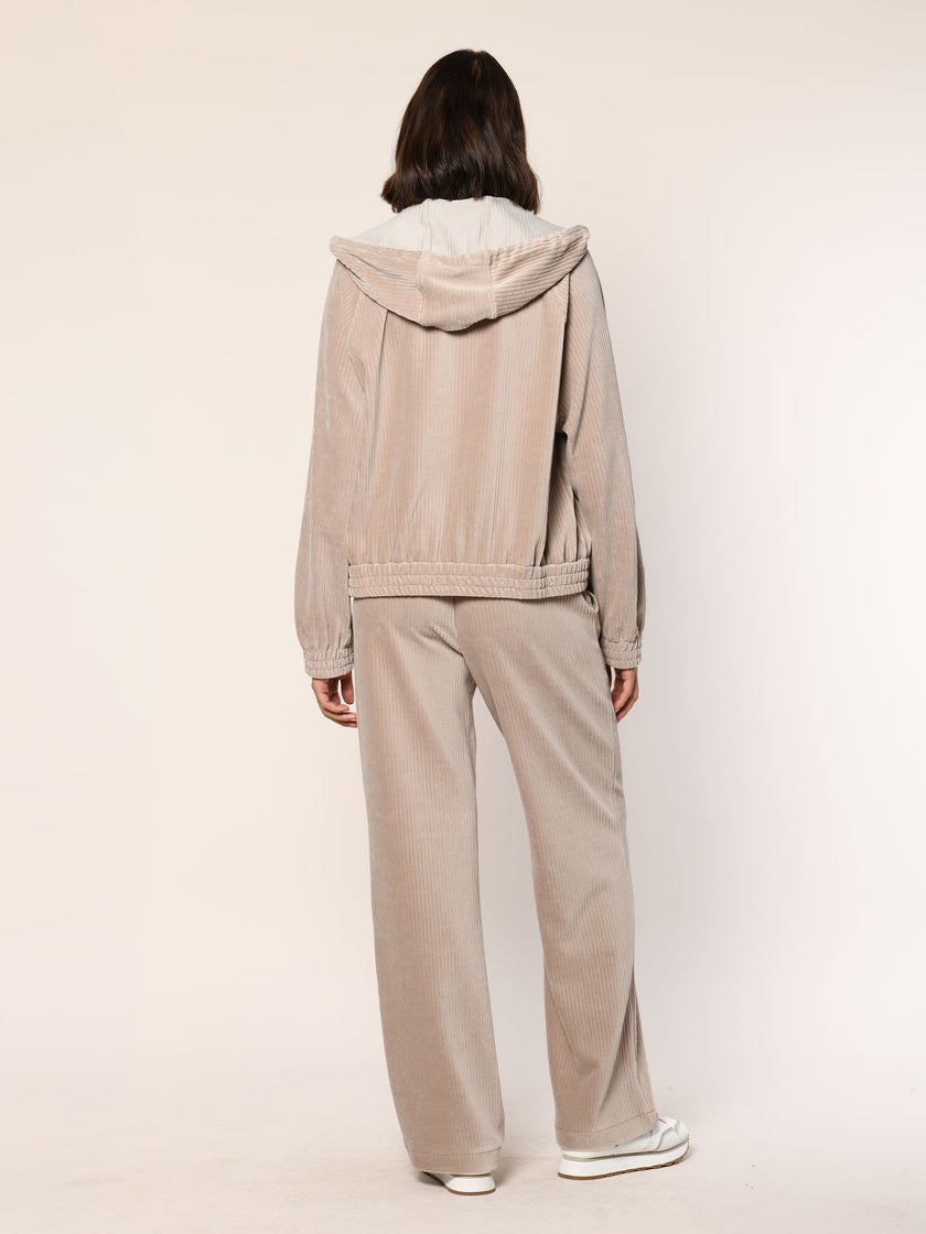 Model trägt Baumwoll Jersey Cord Blouson mit Kapuze in der Farbe Beige - Rückansicht.