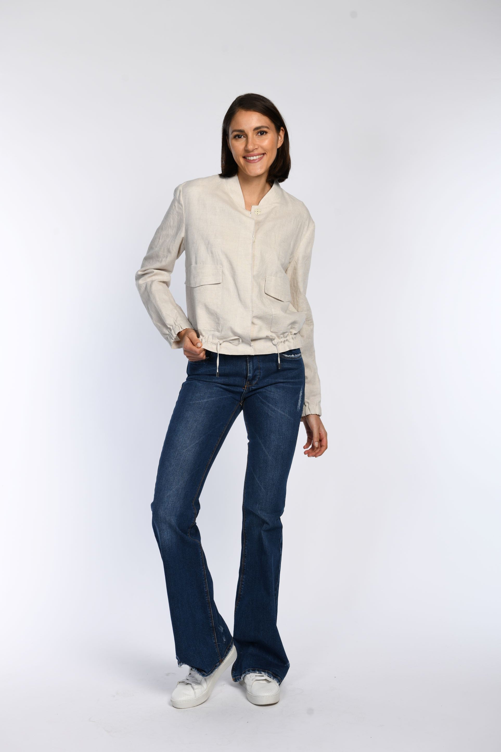 Model trägt ein geschlossenes beiges Blouson aus Leinen mit Stehkragen.