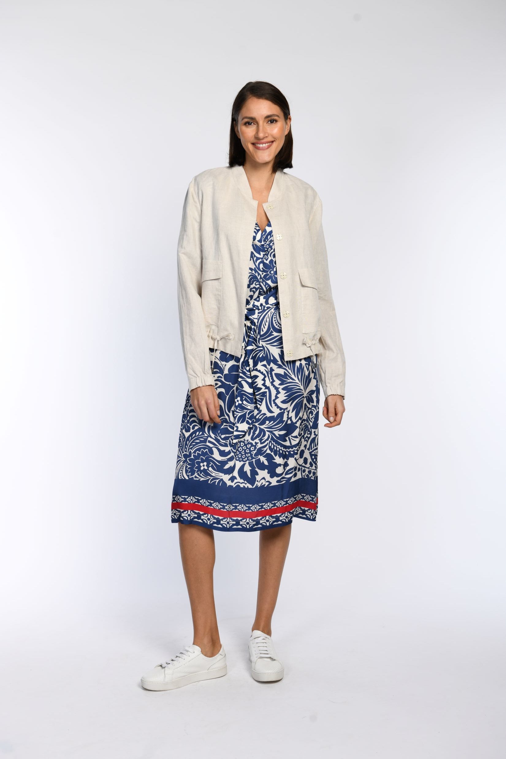 Model trägt ein beiges Leinen-Blouson in Kombination zu einem blau-beigen Tunikakleid.