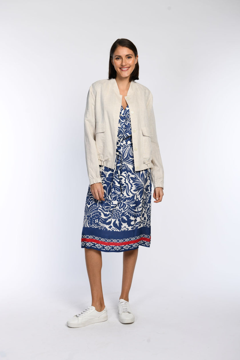 Model trägt ein beiges Leinen-Blouson in Kombination zu einem blau-beigen Tunikakleid.