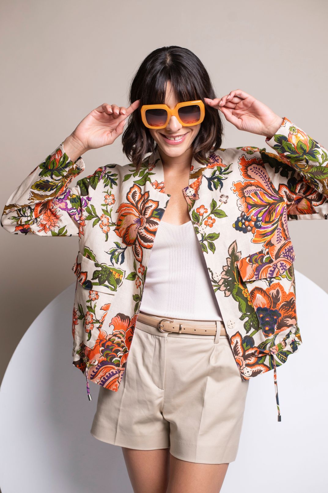 Model trägt sommerliches Blouson mit Floraldruck, kombiniert mit weißem Top und kurzer beiger Hose.