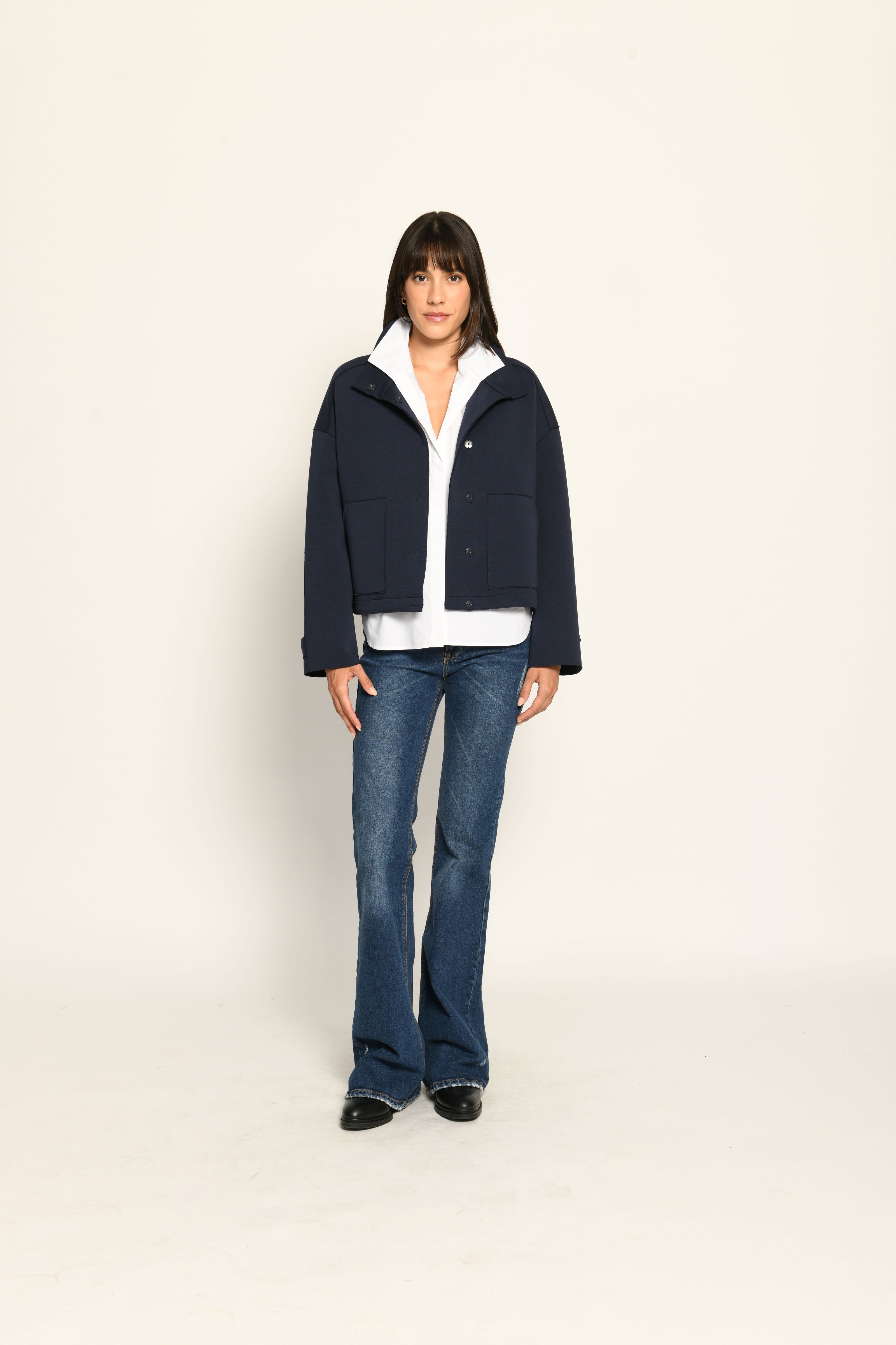 Model trägt dunkelblauen Blouson für Damen aus Scuba, lässig kombiniert zu einer weißen Bluse – Vorderansicht
