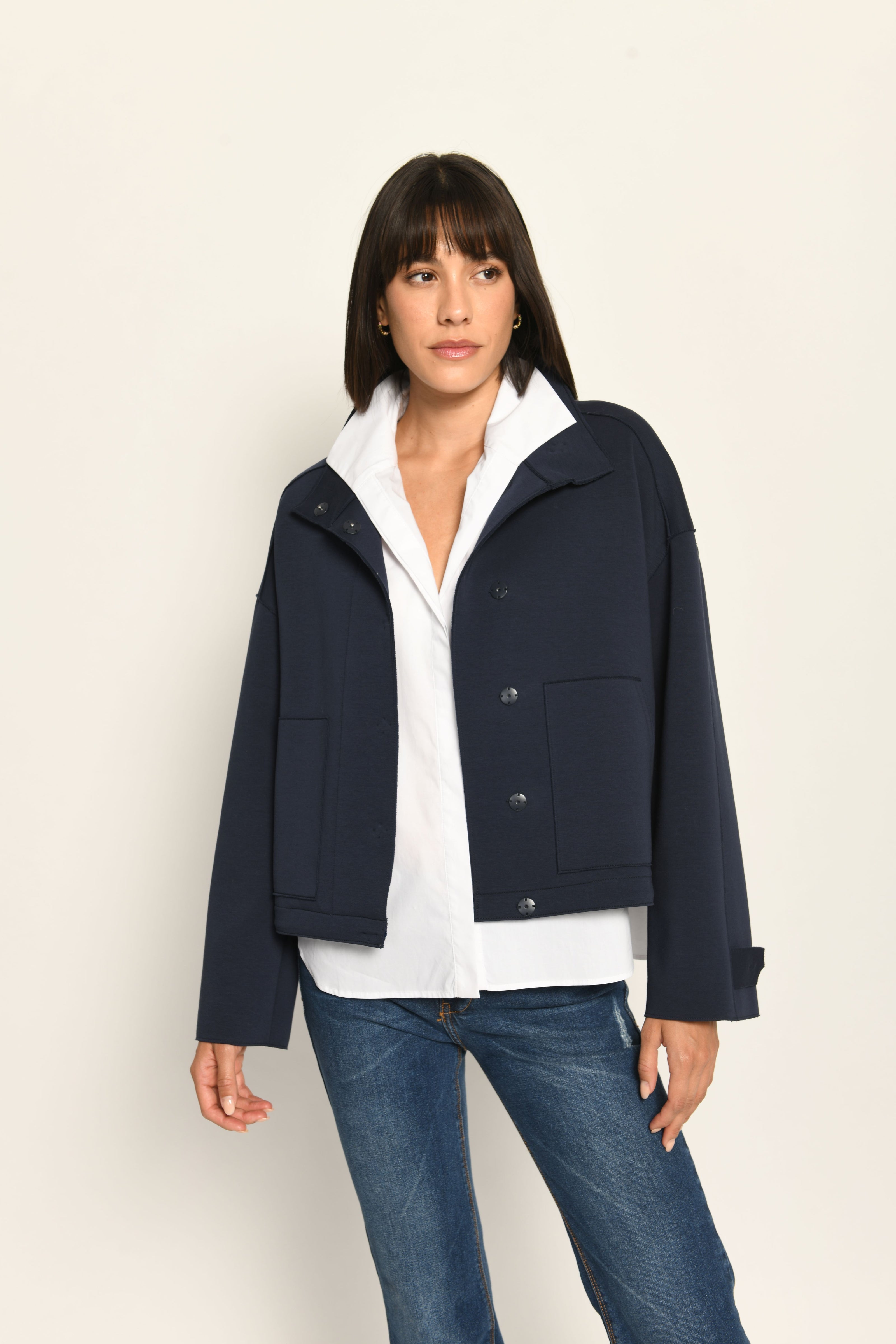 Model trägt dunkelblauen Blouson für Damen aus Scuba, lässig kombiniert zu einer weißen Bluse – Vorderseite